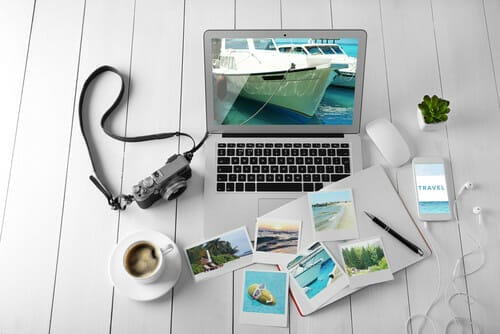 フランスの木製テーブルの上に写真が入ったノートパソコンとコーヒーカップ。