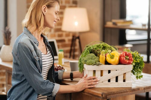 フランスの女性が野菜の入った木箱を抱えています。