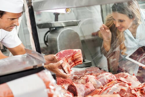 フランスの店で男性と女性が肉を見ている。