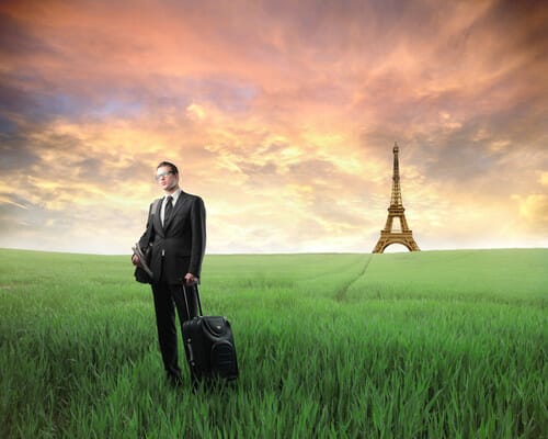 フランスのエッフェル塔近くの野原にスーツを着た男性が立っている。