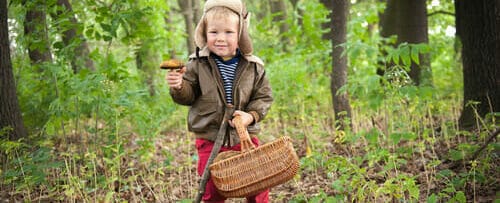 フランスの森の中でキノコの入ったかごを持つ少女。