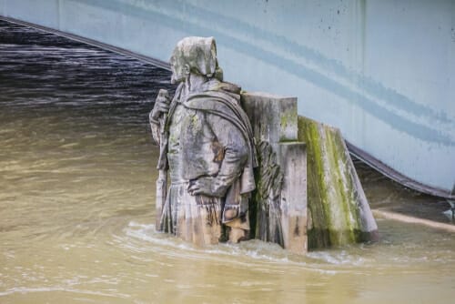 フランスの橋の下の水中に立つ男性の像。