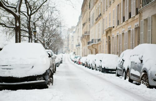 フランス、パリの雪の多い路上に駐車された車。