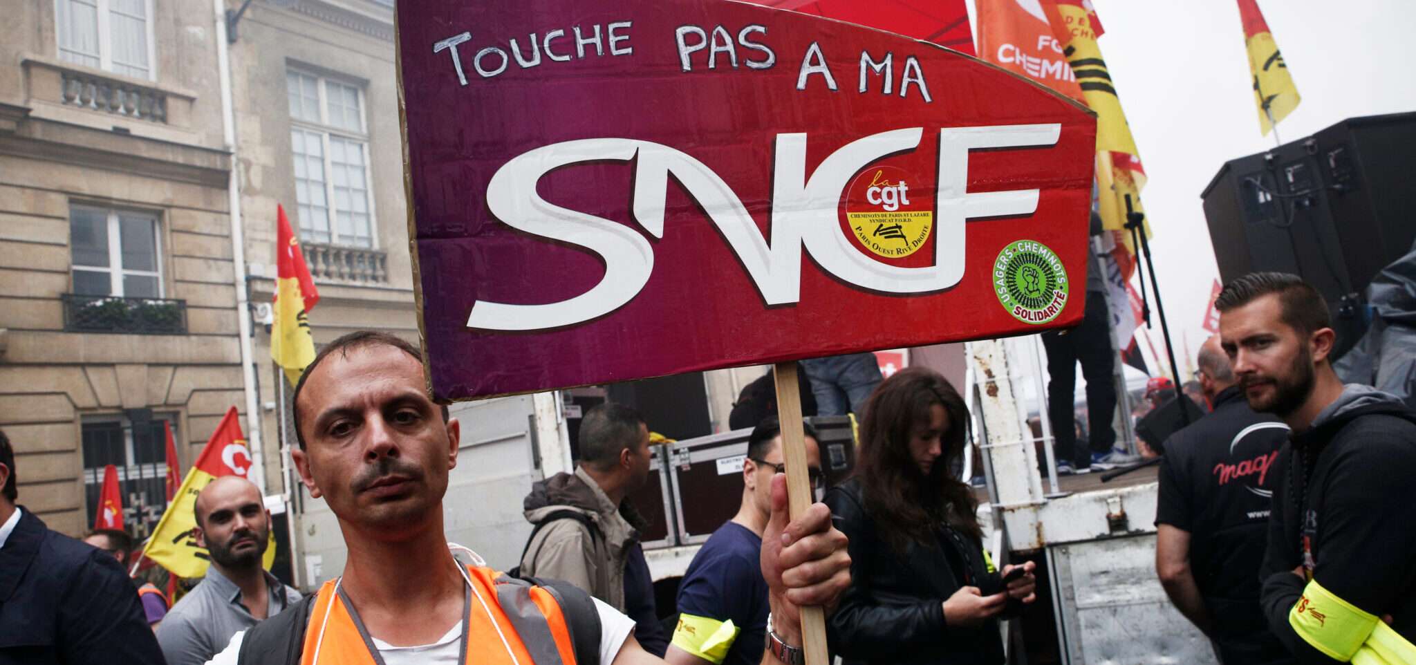 sncfと書かれた看板を持ったフランス人男性。