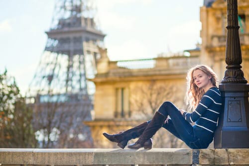 フランスのエッフェル塔の前の手すりに座る若い女性。