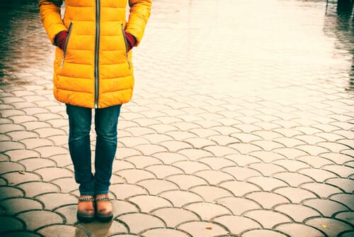 フランスで雨の中立っている黄色いコートを着た女性。