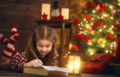 フランスのクリスマスツリーの前で小さな女の子が本を読んでいます。