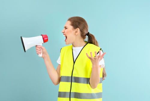 メガホンに向かって叫ぶベストを着たフランス人女性。 メガホンに向かって叫ぶベストを着たフランス人女性。