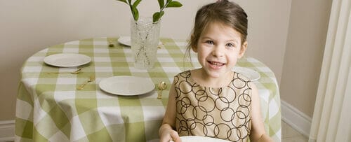 フランスのテーブルの前でお皿を持つ少女。