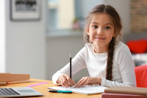 女の子が机に座って、フランスについてノートに書いています。