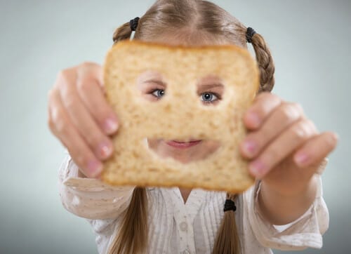 フランス滞在中に、笑顔が描かれたパンを掲げる女の子。