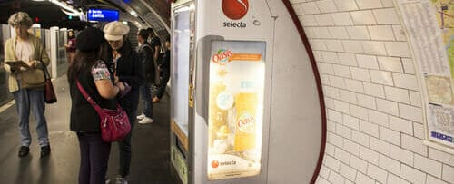 フランスの地下鉄駅の自動販売機の隣に立つ 2 人。