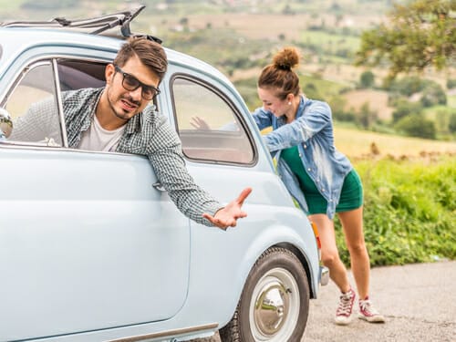 フランスで青い車の隣に立つ男性と女性。