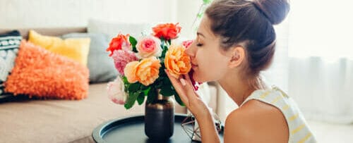 フランスのリビングルームで女性が花瓶の花の香りを嗅いでいます。