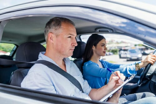 後部座席にクリップボードを積んで車を運転するフランス人観光客。