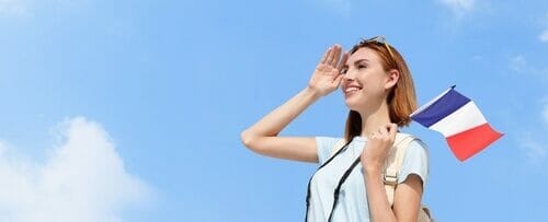 フランス国旗を持って空を見上げているフランス人女性。