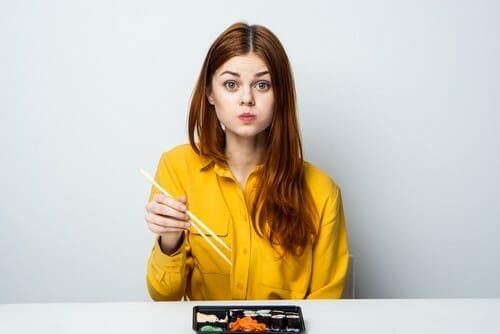 フランスで箸を持ってテーブルに座る赤い髪の女性。