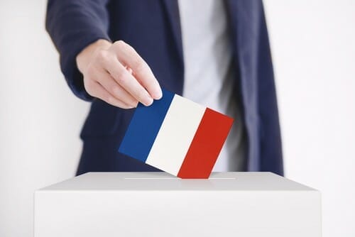 男性がフランス国旗を投票箱に入れています。