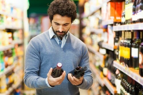 スーパーでフランスのワインのボトルを見ている男性。