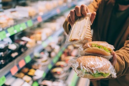 食料品店で、男性がサンドイッチを持っています。