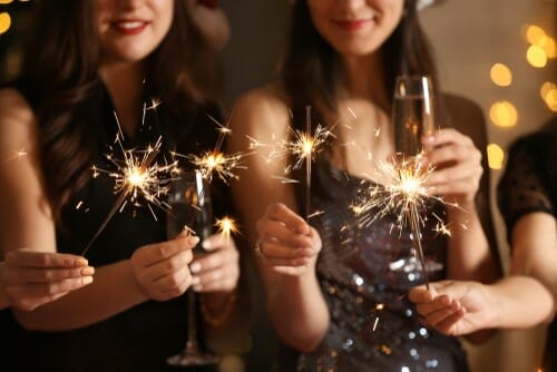 Happy,Women,With,Christmas,Sparklers,And,Glasses,Of,Champagne,At