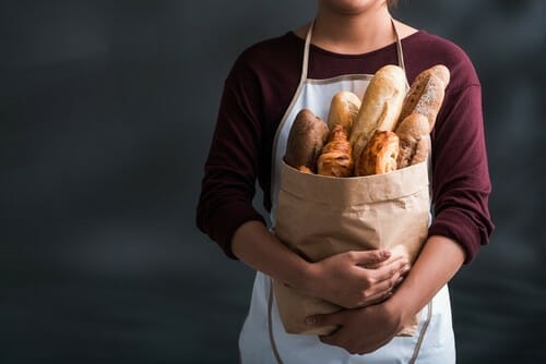 フランスから来た若い女性がパンの入った袋を持っています。