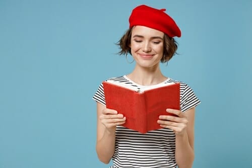 フランスで赤いベレー帽をかぶって本を読んでいる若い女性。