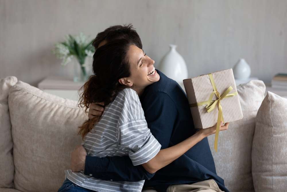 フランスでギフトボックスを持ちながら抱き合う男性と女性。