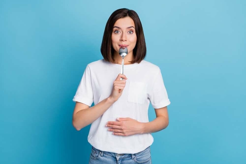 フランスで青い背景の前で歯ブラシを持っている女性。