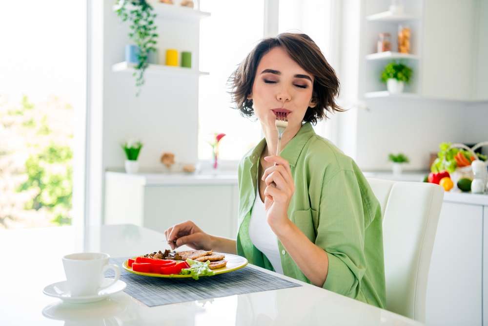 フランスのキッチンで女性が皿に盛られた食べ物を食べている。