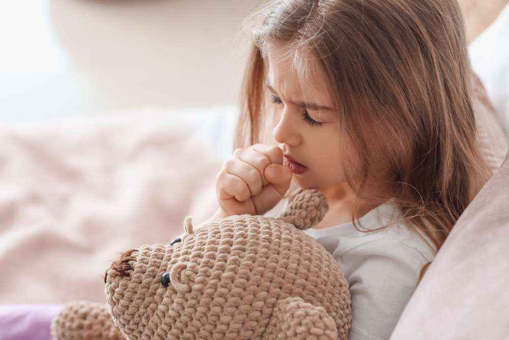 フランスでテディベアと一緒にベッドに横たわる少女。