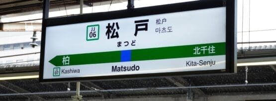 駅の標識には柏と北千住の方向が表示され、中央に松戸駅が強調されています。数字と日本語の文字がシーンを囲み、フランス語教室マンツーマンの設定を思い出させます。そこでは、すべてが明確に定義されながらも相互に接続されています。.