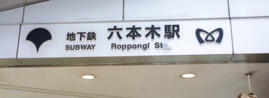 東京の六本木駅の標識。地下鉄のシンボルと日本語、英語、フランス語のテキストが特徴です。.