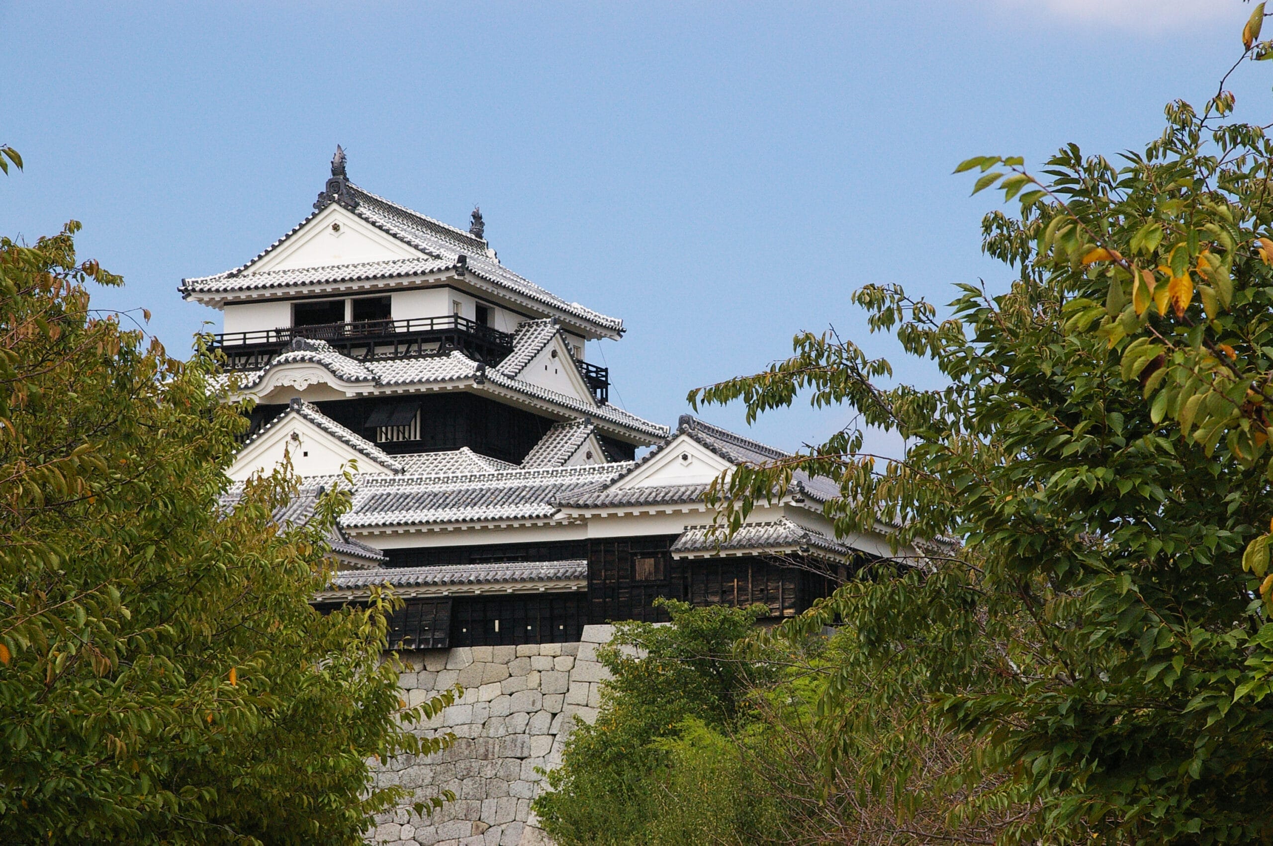 伝統建築の日本の城が堂々と建っており、三重の屋根と石の基礎が特徴で、フランス語教室マンツーマン愛媛・松山で培われた洗練された気品によく似ています。澄んだ青い空の下、緑豊かな木々に囲まれ、さまざまな文化が融合した穏やかな場所です。.