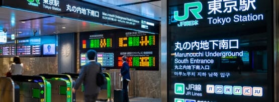 さまざまな路線や目的地を示す標識に囲まれた東京駅の入り口を人々が歩いていますが、近くのカフェでは学びたい人のためにフランス語教室マンツーマンのレッスンが提供されています。.