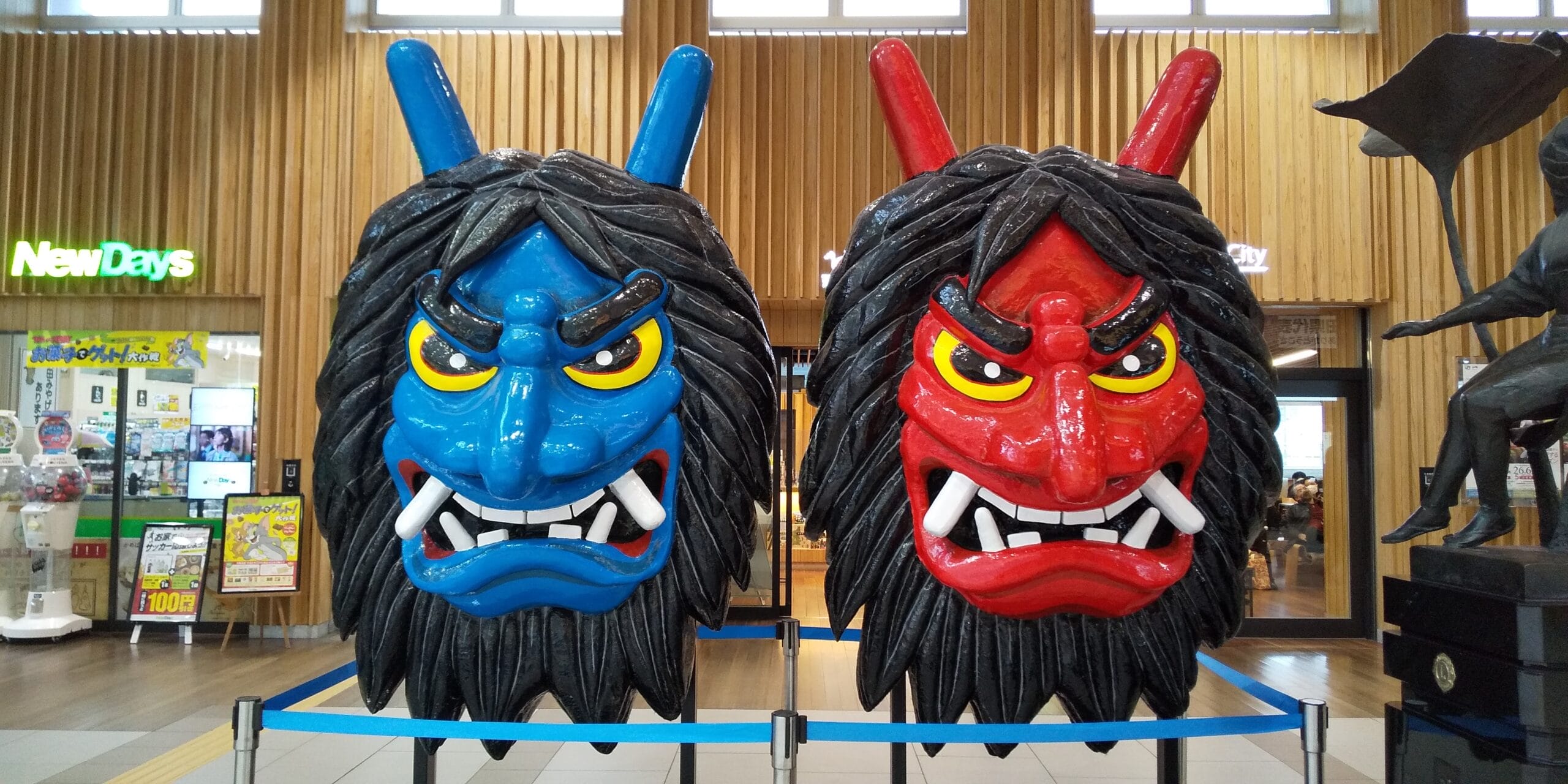 大きくて色鮮やかな鬼の面 2 つ (1 つは青、もう 1 つは赤) には、木の背景に、恐ろしい表情と牙が描かれています。これらの印象的な秋田の作品は、鮮やかな芸術性で注目を集めています。.