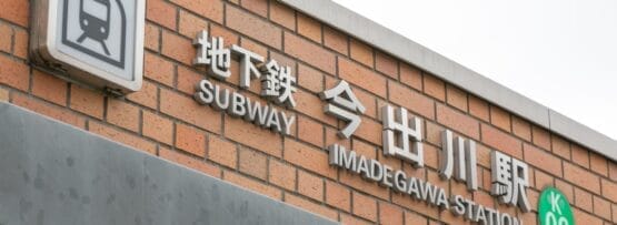 今出川駅のレンガ壁の標識には、地下鉄のアイコンと日本語、英語、フランス語の文字が描かれており、駅コード K06 が強調されています。活気に満ちた雰囲気は京都の多文化の本質を反映しており、マンツーマンのフランス語クラスに最適な場所です。.