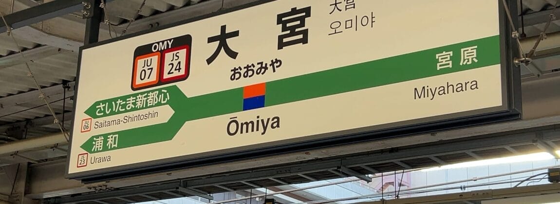 大宮駅の標識には、プラットフォームの詳細やさいたま新都心駅、宮原駅などの隣接駅が表示されており、日本語、英語、韓国語、さらには語学レッスンを求める旅行者のニーズに応えるためにフランス語でも案内されています。.